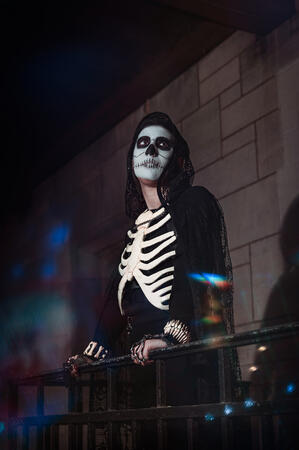 Ragsy's cosplay of Harrow from The Locked Tomb, leaning against a metal railing and gazing into the distance.